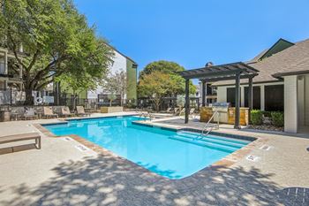 A large outdoor swimming pool surrounded by trees and a building.